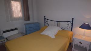 a bedroom with a yellow bed with a lamp and a dresser at Joli Pavillon 2** Narbonne Plage in Narbonne-Plage