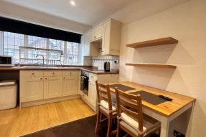 una cocina con mesa de madera y sillas. en One-Bedroom flat in Cheam Village en Cheam