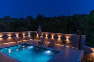 a swimming pool on a patio at night with lights at Luxury Nest Maretta & Oliva in Korčula