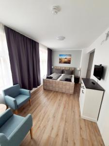 een slaapkamer met een bed, een bank en een televisie bij Hafen Appartements Wismar in Wismar