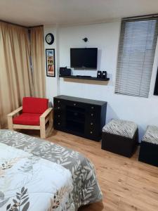 um quarto com uma cama, uma televisão e uma cadeira em Hospedaje Aguaclara em Quito