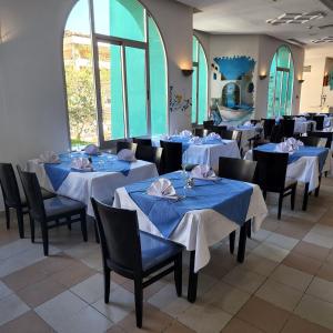 jadalnia z niebieskimi stołami, krzesłami i oknami w obiekcie Golf Beach & Thalasso- Families and Couples w mieście Triffa
