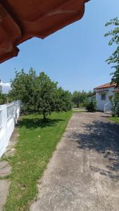 a dirt road with a tree and a white fence at Vasiliki's guest house in Vergia +8 photos