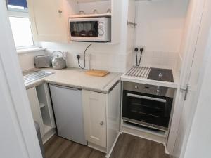 a small kitchen with a stove and a microwave at 1 Trevelyan in Helston
