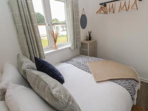 um quarto com uma cama com almofadas e uma janela em 1 Trevelyan em Helston