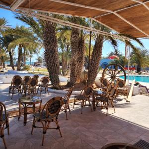 a patio with tables and chairs and palm trees at Golf Beach & Thalasso- Families and Couples in Triffa