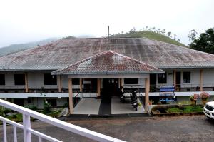 uma casa com um telhado de azulejo com um corrimão branco em AC MIST em Munnar