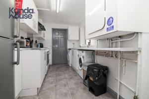 a kitchen with white cabinets and a washer and dryer at Kunda House Old Grange in Birmingham