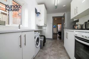 a kitchen with white cabinets and a washer and dryer at Kunda House Old Grange in Birmingham