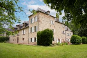 a large brick building with a grass yard at La Demeure du Comte in Marcillac-Vallon