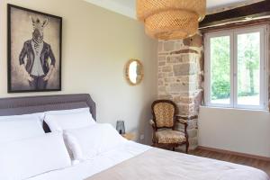 a bedroom with a bed and a chair and a window at La Demeure du Comte in Marcillac-Vallon