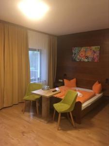 1 dormitorio con 1 cama y 1 mesa con sillas verdes en Aineterhof, en Ainet