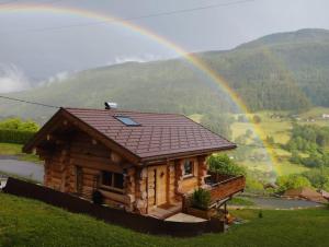 einen Regenbogen über einer Blockhütte mit in der Unterkunft Chalet Anzac Chalet 5 Etoiles en Rondins Tout Neuf Unique dans les Aravis in Les Villards-sur-Thônes