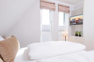 a white bedroom with a white bed and a window at Ferienhaus Witthüs - Domizil Silbermöwe - exklusiv, strand- und zentrumsnah in Westerland (Sylt)