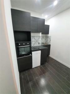 uma cozinha com armários pretos e piso em azulejo em Villeurbanne 100 m2 Superbe appartement 3 Chambres, 3 salle de bains em Villeurbanne