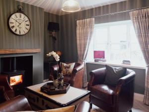 a living room with chairs and a clock on the wall at Stag Cottage in Macclesfield