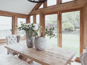 due vasi seduti su un tavolo di legno con fiori di Stag Cottage a Macclesfield