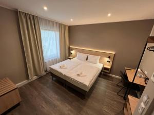 una camera da letto con letto, lenzuola e cuscini bianchi di JJ Hotel Hannover-City-Pension ad Hannover
