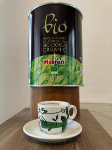 una taza de café sentada en un plato junto a una lata de mojo en B&B Casa Wanda since 1999, en Riva del Garda
