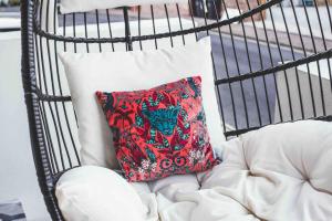 a red pillow sitting on a white chair at Stoke Fleming Studio Apartment in Stoke Fleming