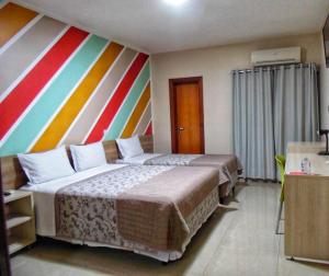 two beds in a hotel room with a colorful wall at MAPER MARDAN in Parauapebas +20 photos