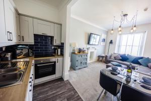 a kitchen and living room with a couch and a table at Flat 3 Flint House Tenby - Luxury couples apartment in Tenby