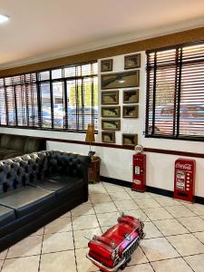 a living room with a black couch and a red car on the floor at Hotel Bons Tempos in Rio Verde