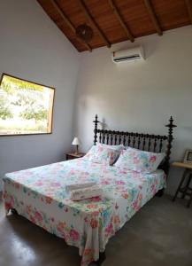 a bedroom with a bed with a floral bedspread at Fazenda Bom Sossego - Corumbau, BA in Corumbau