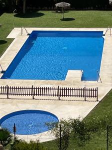 una gran piscina azul con una valla alrededor en Encantador Piso con Terraza y Piscina, en Benalmádena
