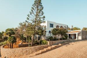 ein Haus mit einer Steinmauer und einem Baum in der Unterkunft Finca Norte, Amazing villa close to the best Beaches in Portinatx