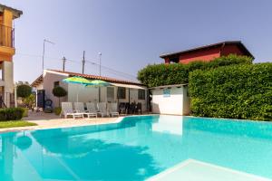 a blue swimming pool with an umbrella next to a house at Villa Arianna in Ragusa