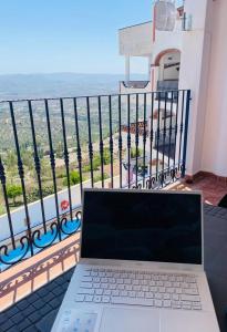 un computer portatile seduto su un tavolo di fronte a un balcone di Apartamento La Fuente Alcaucin ad Alcaucín