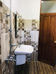 baño con lavabo blanco y puerta de madera en Thammenna Eco Cabins, en Dambulla