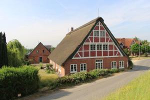 een groot gebouw van rode baksteen met een rieten dak bij Ferienhaus Alwine in Jork