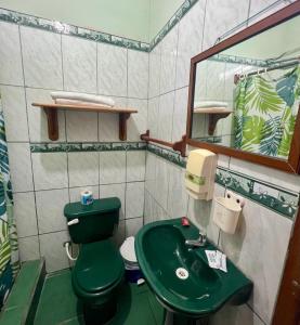 a bathroom with a green toilet and a green sink at Hostal Villamil in Puerto Villamil