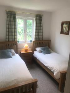 a bedroom with two beds and a window at Liming Lodge - Lakeside Home in the Cotswolds in South Cerney