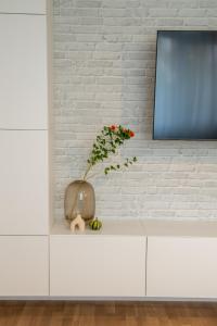 a vase with a flower sitting on a white cabinet at Andor apartment near park and subway in Bucharest