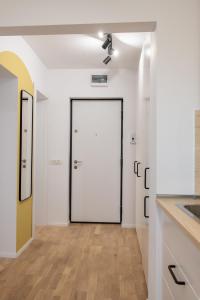 a hallway with a white door and a wooden floor at Andor apartment near park and subway in Bucharest