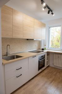 a kitchen with white cabinets and a sink and a window at Andor apartment near park and subway in Bucharest