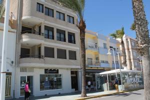 a building on a street with palm trees in front of it at Apartamento Avenida Mar in Peniscola