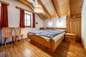 una camera con un letto in legno e due sedie di Lindenhof Apt 1 a Vandoies
