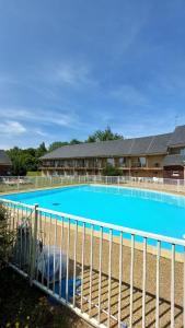 une grande piscine bleue derrière une clôture dans l'établissement L’entrelacs, à Équemauville