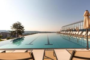 a large swimming pool with chairs and umbrellas at Fruške Residences in Vrdnik