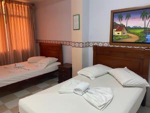 two beds in a room with a painting on the wall at Hotel Los Corales Tulua in Tuluá