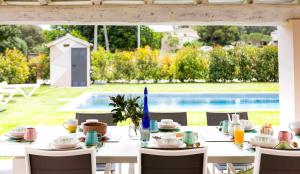einen Tisch für eine Mahlzeit neben einem Pool in der Unterkunft Can Candiu Establecimiento de 2 casas enteras in Vall-llobrega