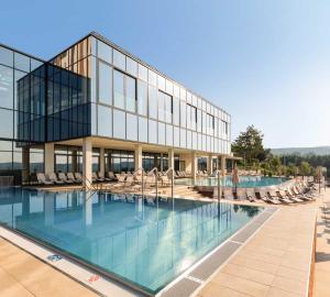 a large building with a swimming pool and chairs at Fruške Residences in Vrdnik
