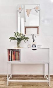 a white console table with a vase of flowers and a mirror at Tiber Rooms Testaccio in Rome