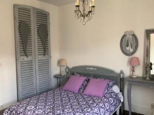 a bedroom with a bed with purple pillows and a chandelier at Hyper Centre Fontainebleau Villa Beau Soleil in Fontainebleau