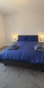 a bedroom with a bed with blue sheets and two lamps at Causeway Coast Sea Shore Apartment - Ballycastle in Ballycastle
