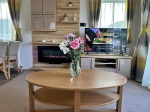 a vase of flowers sitting on a table in a living room at Highland Holiday Getaways in Embo